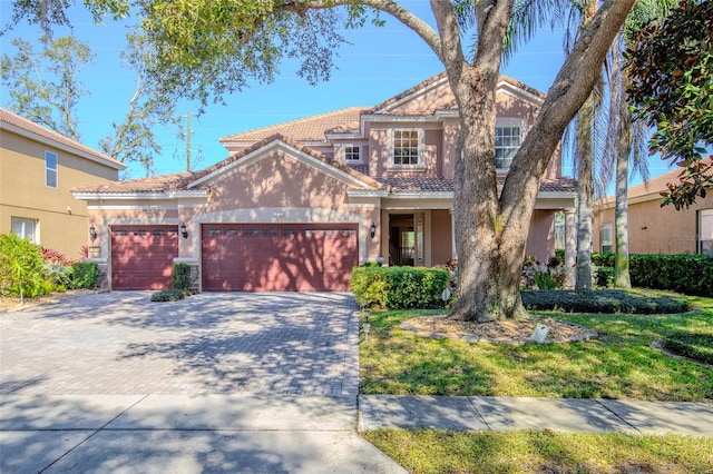 view of front facade with a garage, a tiled roof, decorative driveway, and stucco siding