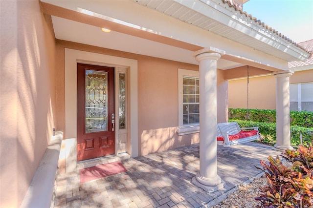 doorway to property with covered porch and stucco siding