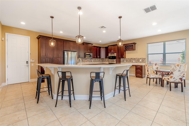 kitchen with appliances with stainless steel finishes, light countertops, visible vents, and backsplash