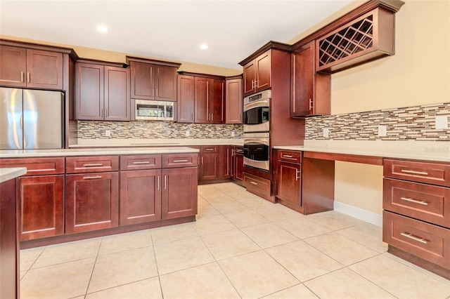 kitchen with reddish brown cabinets, light tile patterned floors, decorative backsplash, appliances with stainless steel finishes, and light countertops