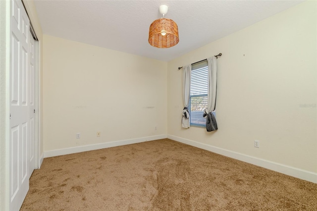 unfurnished room featuring a textured ceiling, baseboards, and carpet flooring