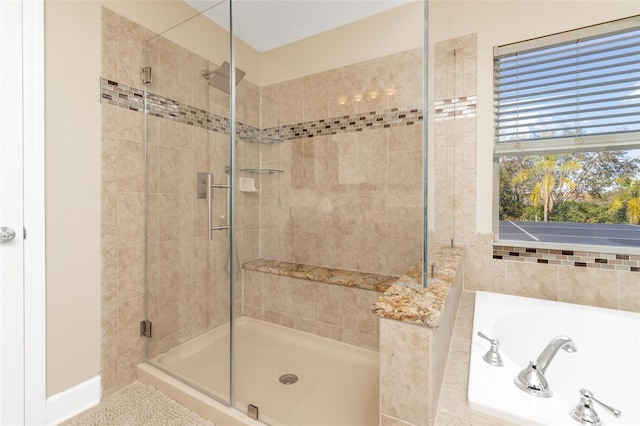 full bathroom with a garden tub, a shower stall, and baseboards