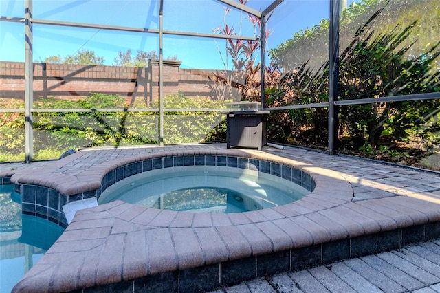 pool with glass enclosure, fence, and an in ground hot tub