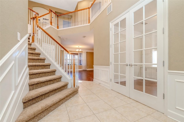 staircase featuring tile patterned flooring, french doors, and a decorative wall