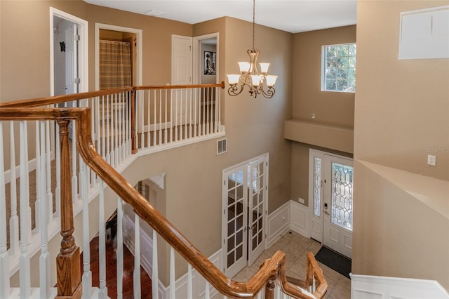 stairway with a chandelier, a wainscoted wall, and visible vents