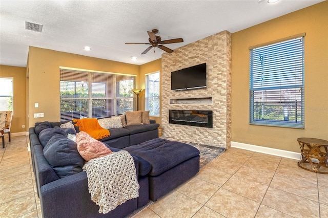 living area featuring a textured ceiling, a stone fireplace, visible vents, and a healthy amount of sunlight