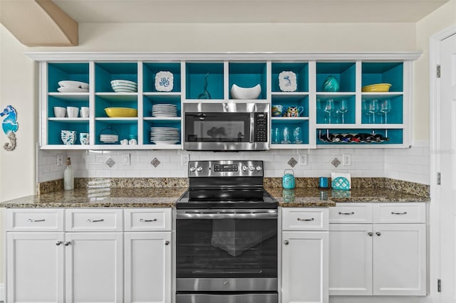 kitchen featuring dark stone countertops, backsplash, white cabinets, and appliances with stainless steel finishes