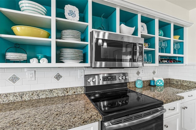 kitchen with tasteful backsplash, stainless steel appliances, dark stone countertops, and white cabinets