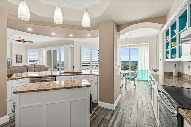 kitchen with sink, appliances with stainless steel finishes, white cabinetry, a kitchen island, and decorative light fixtures