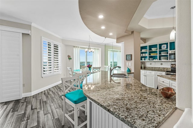 kitchen featuring hanging light fixtures, sink, white cabinets, and stone counters