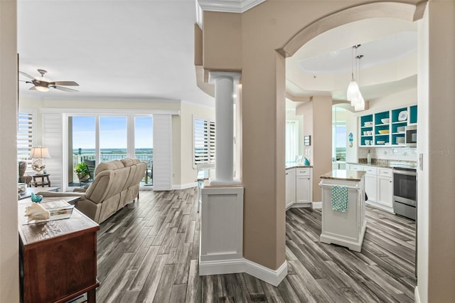 kitchen with white cabinetry, stainless steel appliances, dark hardwood / wood-style flooring, decorative light fixtures, and ornate columns