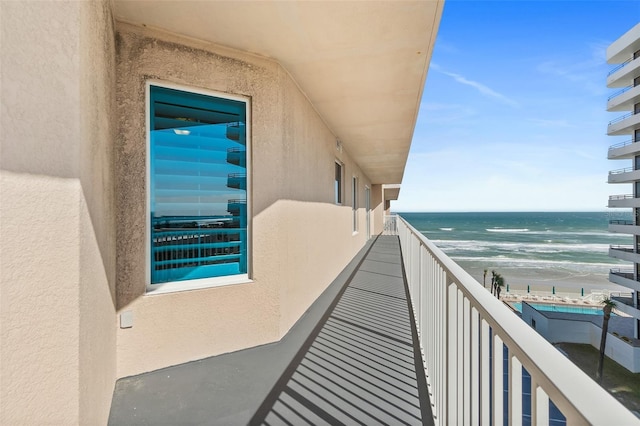 balcony featuring a view of the beach and a water view