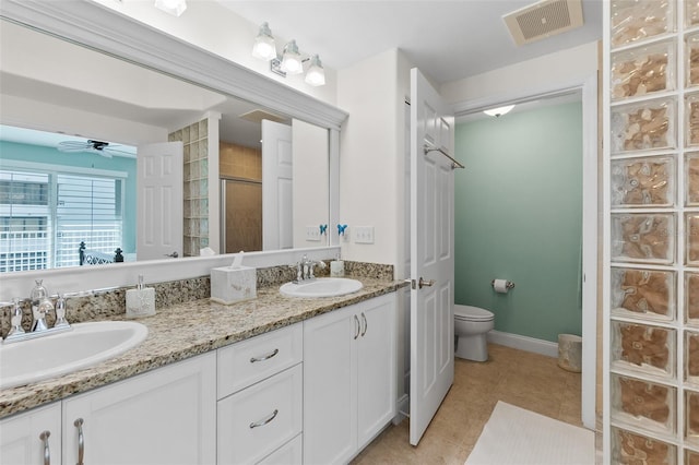 bathroom featuring tile patterned floors, toilet, vanity, a shower with door, and ceiling fan