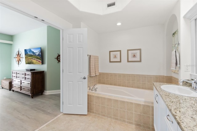 bathroom with vanity, a relaxing tiled tub, and tile patterned floors