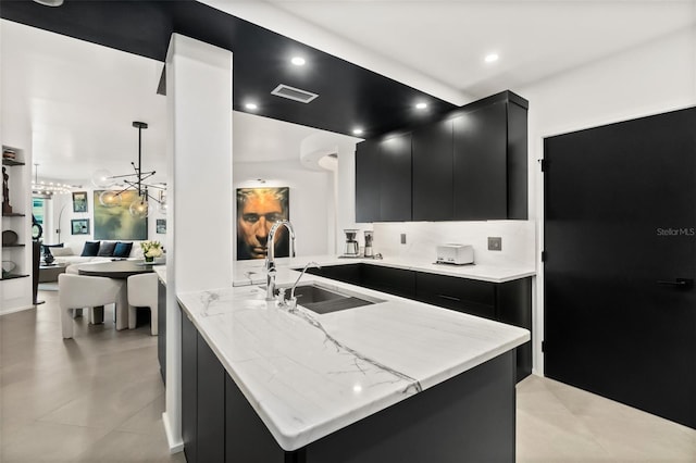 kitchen with sink, hanging light fixtures, light tile patterned floors, kitchen peninsula, and light stone countertops