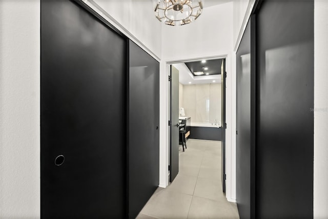 hallway with light tile patterned floors and a tray ceiling