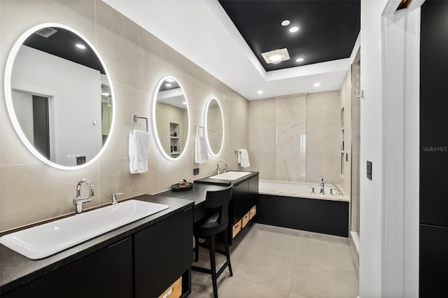 bathroom featuring a raised ceiling, shower with separate bathtub, tile walls, and vanity