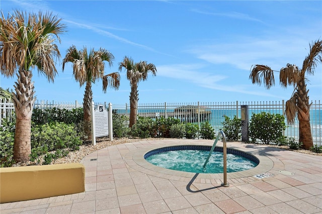 view of swimming pool featuring a hot tub and a water view