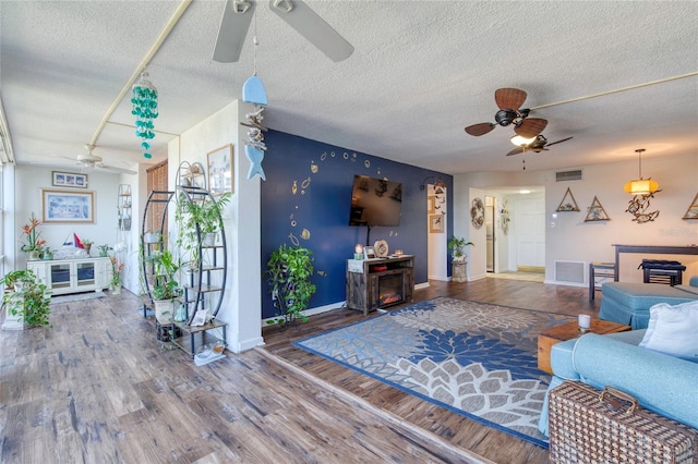 living room featuring ceiling fan, hardwood / wood-style floors, and a textured ceiling