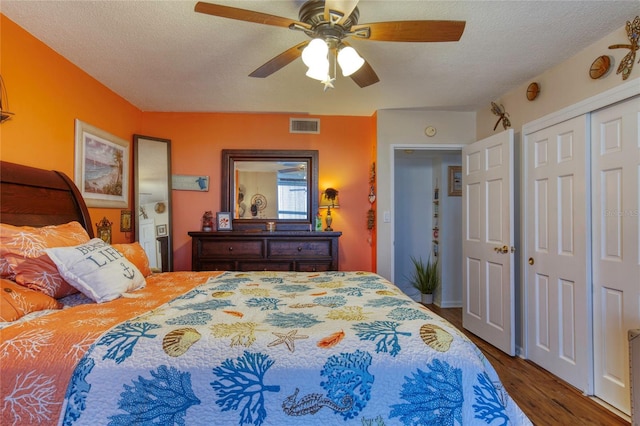 bedroom featuring ceiling fan, dark hardwood / wood-style floors, a closet, and a textured ceiling