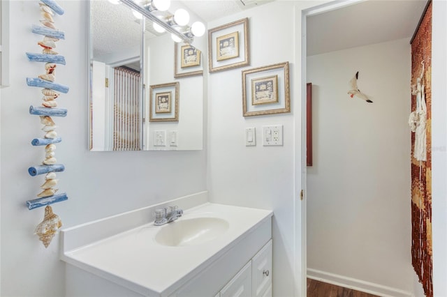 bathroom with hardwood / wood-style flooring, vanity, and a textured ceiling