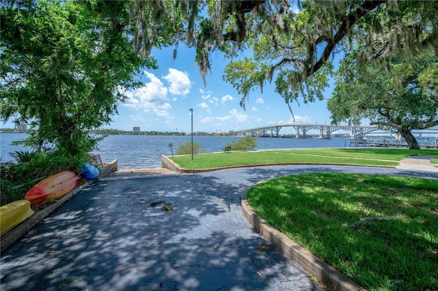 surrounding community featuring a water view and a lawn