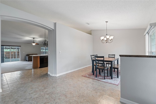 dining area featuring ceiling fan with notable chandelier and a textured ceiling