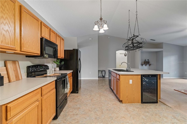 kitchen featuring pendant lighting, sink, black appliances, a center island with sink, and beverage cooler