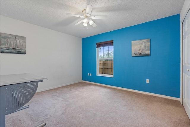 carpeted empty room with ceiling fan and a textured ceiling