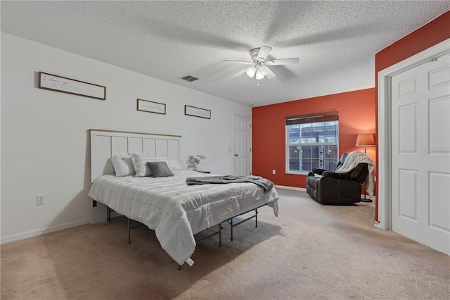 bedroom featuring a textured ceiling, light colored carpet, and ceiling fan