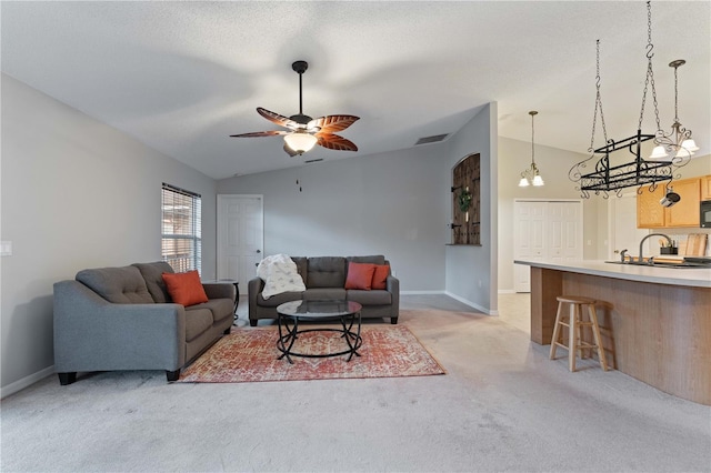 living room with sink, ceiling fan, a textured ceiling, vaulted ceiling, and light colored carpet