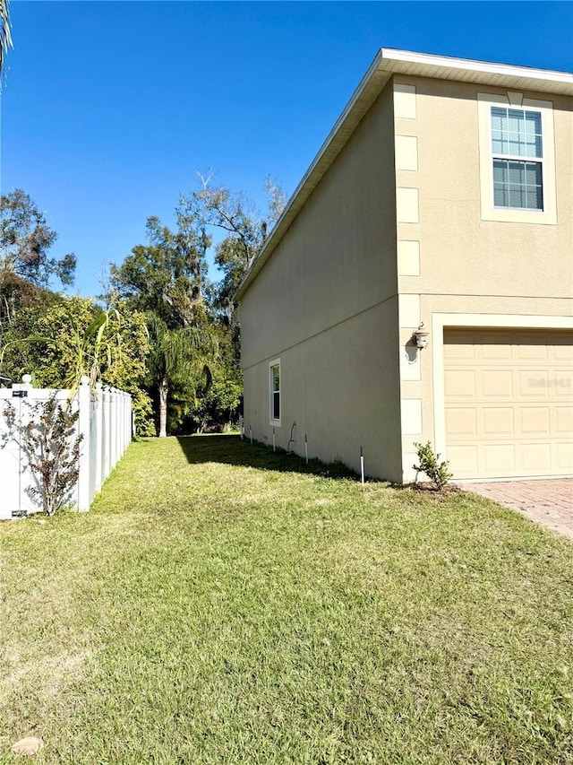 view of side of property featuring a garage and a lawn