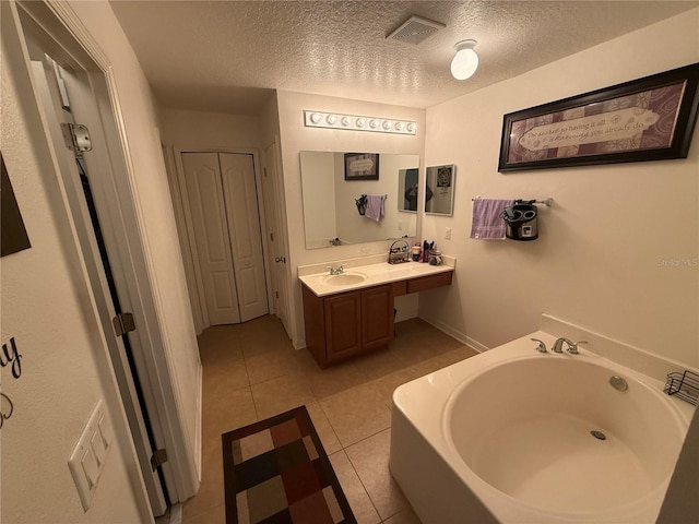 bathroom featuring vanity, a bath, tile patterned floors, and a textured ceiling