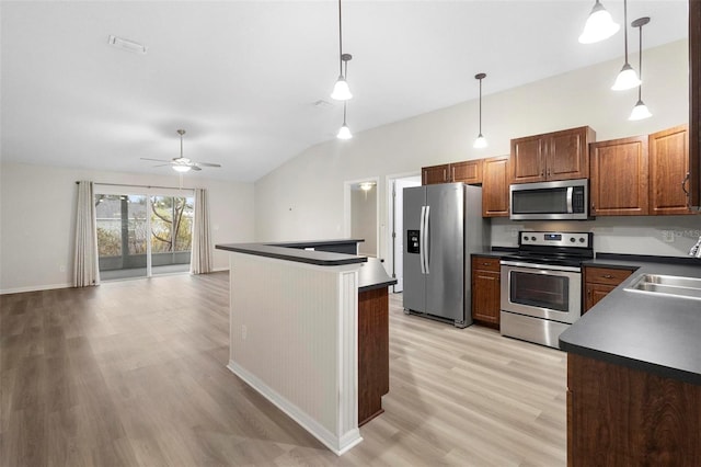 kitchen featuring sink, decorative light fixtures, vaulted ceiling, light wood-type flooring, and stainless steel appliances