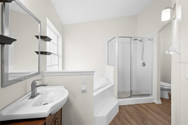 full bathroom with toilet, wood-type flooring, shower with separate bathtub, vaulted ceiling, and vanity