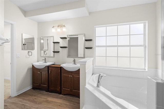 bathroom with a relaxing tiled tub, vanity, and hardwood / wood-style floors