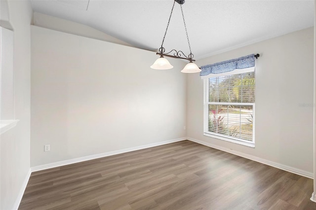 spare room featuring vaulted ceiling and dark hardwood / wood-style floors