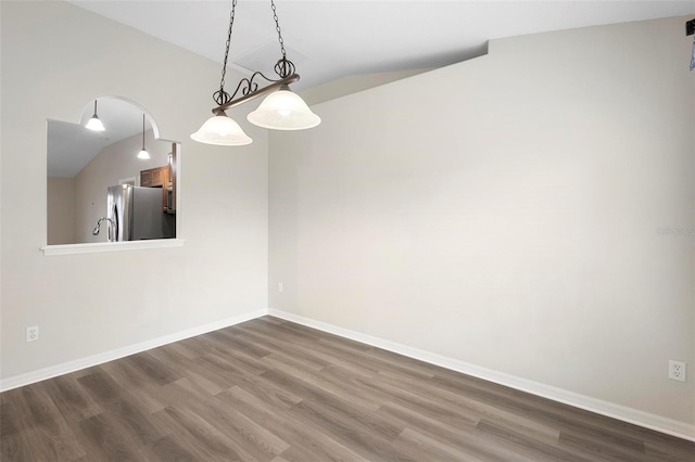 spare room featuring lofted ceiling and dark hardwood / wood-style floors