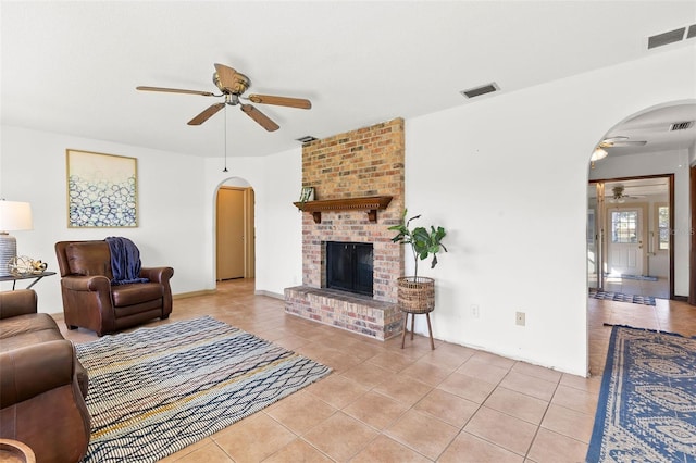 living room featuring light tile patterned floors, a fireplace, and ceiling fan