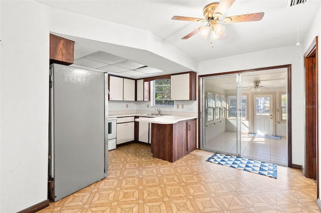 kitchen featuring sink, fridge, kitchen peninsula, electric stove, and white cabinets