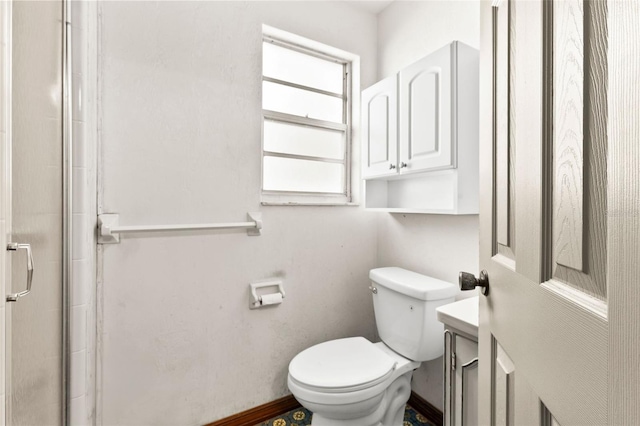 bathroom featuring a shower with door and toilet