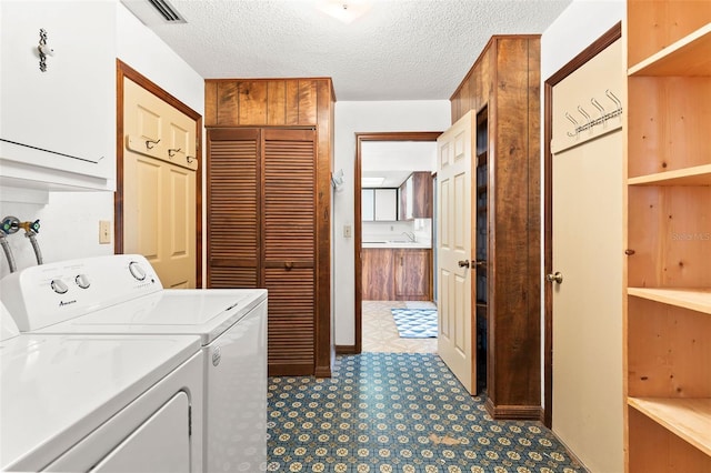 laundry room featuring washer and clothes dryer, cabinets, and a textured ceiling