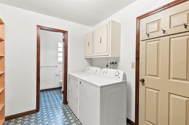 washroom featuring washer and dryer, cabinets, and a textured ceiling