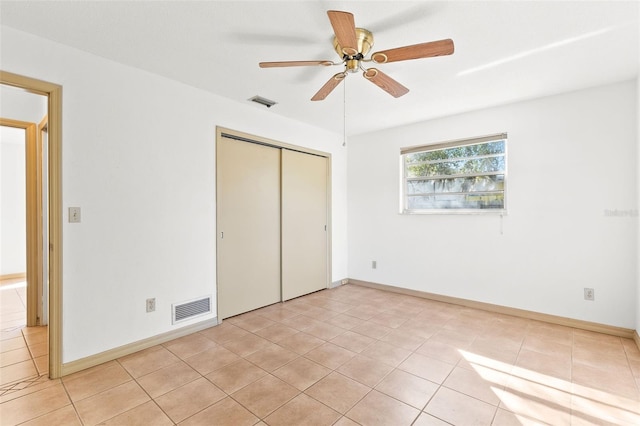 unfurnished bedroom with ceiling fan, a closet, and light tile patterned floors