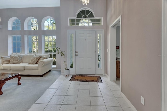 foyer featuring light tile patterned floors, a chandelier, and a high ceiling