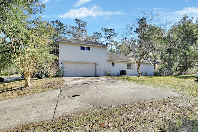 rear view of property featuring a garage, a yard, and cooling unit