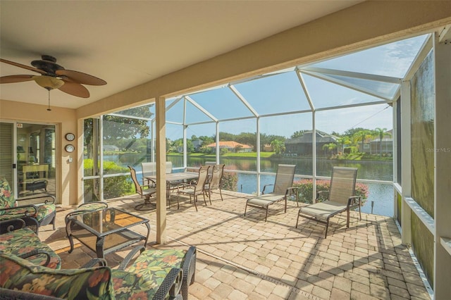 unfurnished sunroom featuring a water view, ceiling fan, and a wealth of natural light