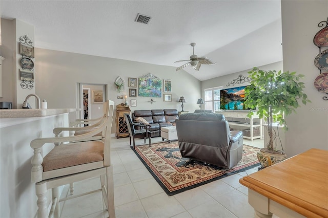 living room featuring vaulted ceiling, sink, light tile patterned floors, ceiling fan, and a textured ceiling