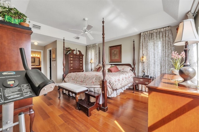 bedroom with ceiling fan, a tray ceiling, and hardwood / wood-style floors