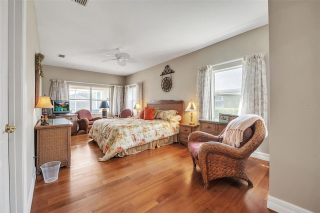 bedroom with ceiling fan, hardwood / wood-style floors, and multiple windows